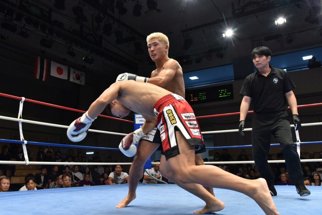 初回、悠の左フックでノックダウンを喫する西田光汰